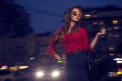 Beautiful sexy caucasian woman with long curly brunette hair and make up on big eyes and full sensual lips. She coming back from party, walking in office dress on european street with traffic lights
